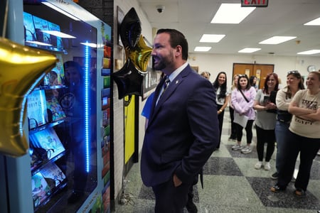 A principal with students at a book vending machine