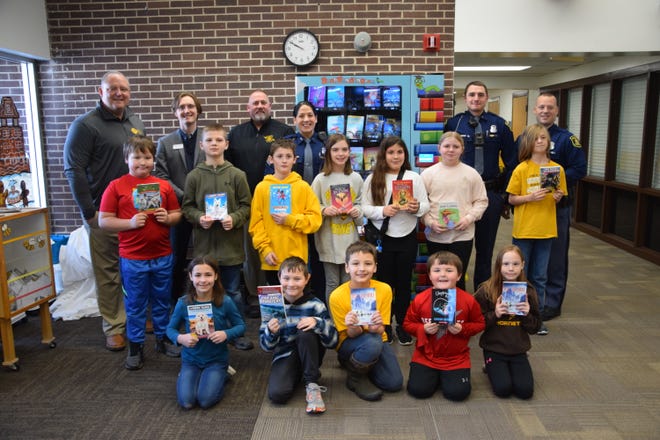 The first batch of book vending machine winners pose with Pellston Superintendent Stephen Seelye, state troopers and Jake Myers, community philanthropy officer for the Petoskey-Harbor Springs Area Community Foundation.
